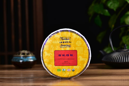 Yellow tea cake with a red label on a wooden surface, blurred background