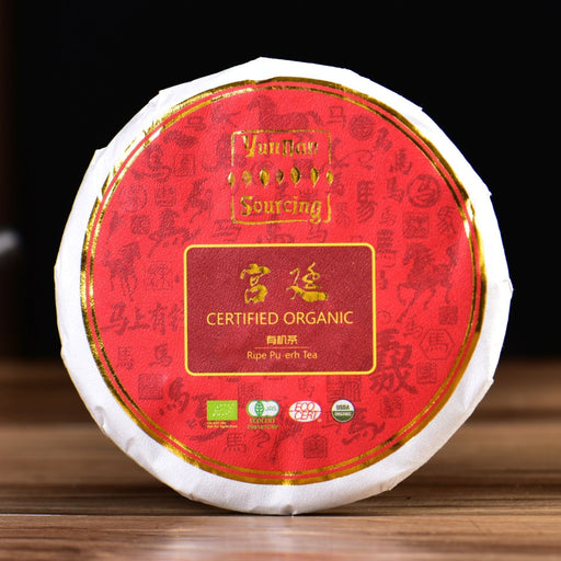 Certified organic tea cake with a red label on a wooden surface, blurred background