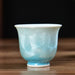 Teal ceramic cups on a wooden surface with a blurred background