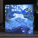 Decorative light box with a nature scene on a wooden surface.