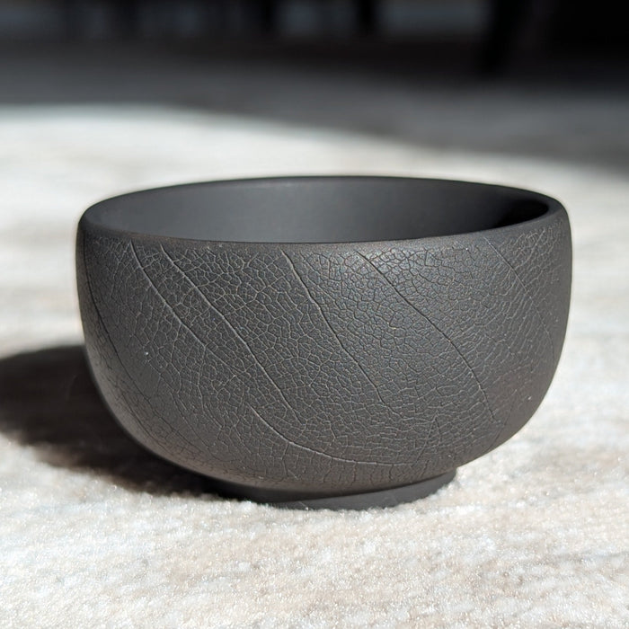 Gray clay cup on a textured surface